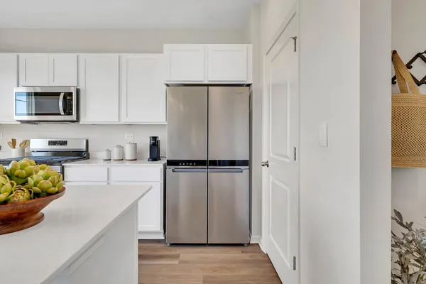 a kitchen with a refrigerator a stove and white cabinets