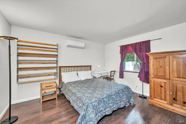 a bedroom with a bed and a dresser with wooden floor