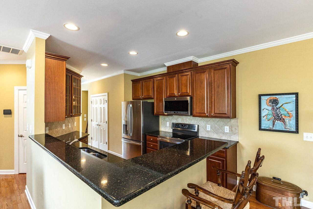 3512 Edgemont Drive Raleigh, NC 27612 - Photo 12 of 30 a kitchen with stainless steel appliances granite countertop a refrigerator a stove and a sink with wooden floor