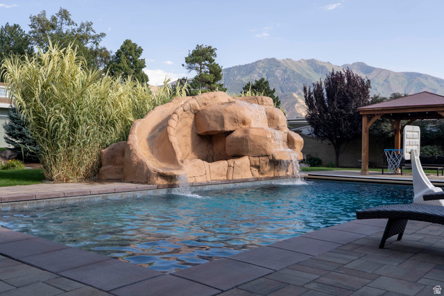 687 South 2080th Street East Springville, UT 84663 - Photo 99 of 149 Outdoor pool area featuring a rock-formation water slide, integrated waterfall, and paver patio