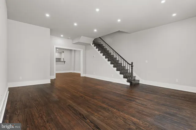 a view of an empty room with wooden floor and stairs