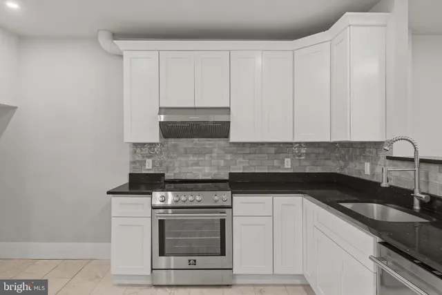 a kitchen with granite countertop white cabinets and stainless steel appliances