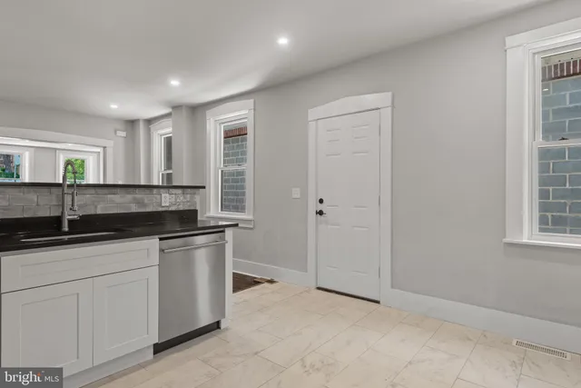a kitchen with granite countertop a sink and white cabinets