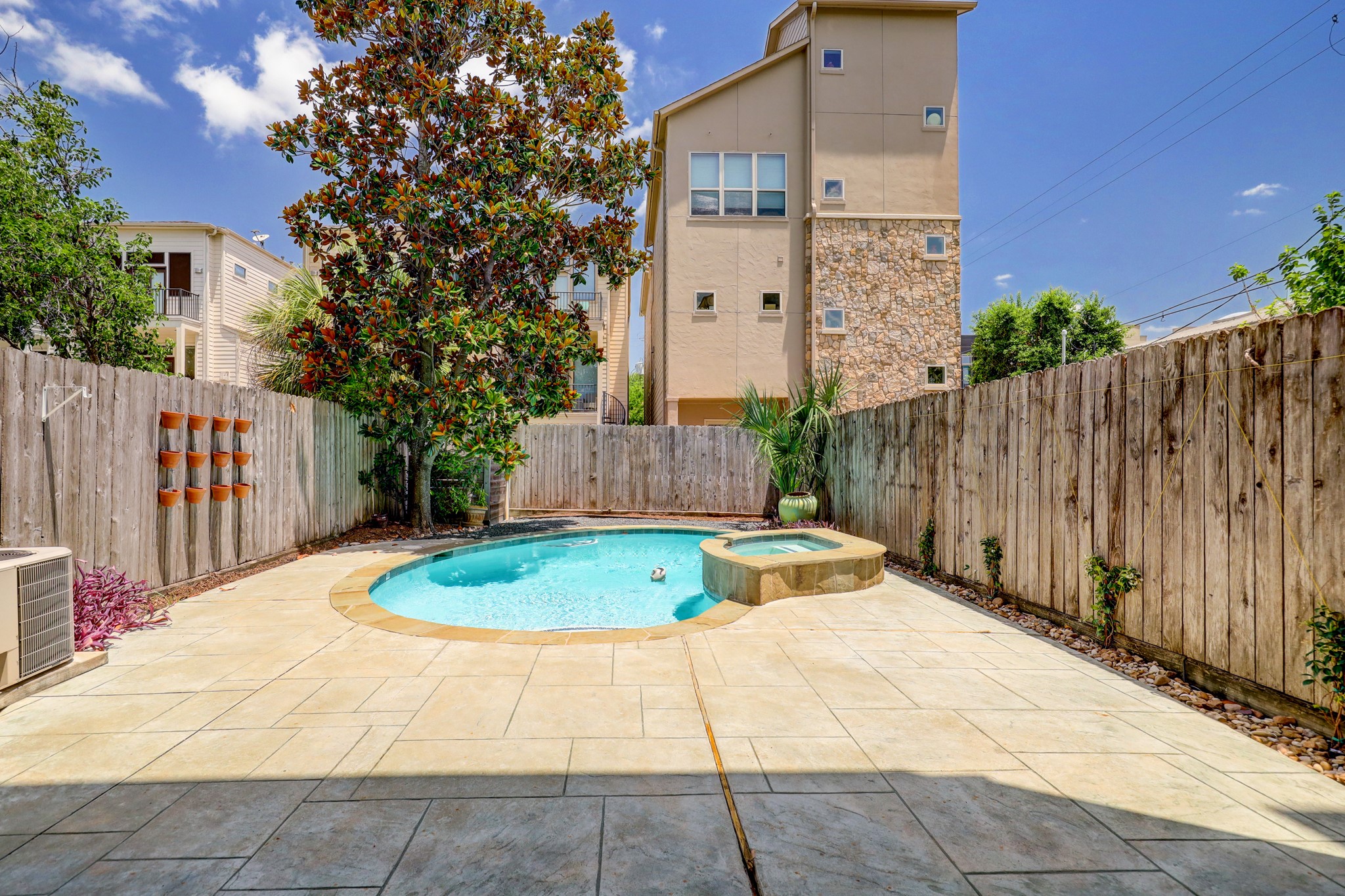 5202 Rose Street, Unit B Houston, TX 77007 - Photo 11 of 40 This backyard features a private pool and spa, surrounded by a wooden fence for added privacy. The area includes a small garden and potted plants, creating a relaxing oasis.