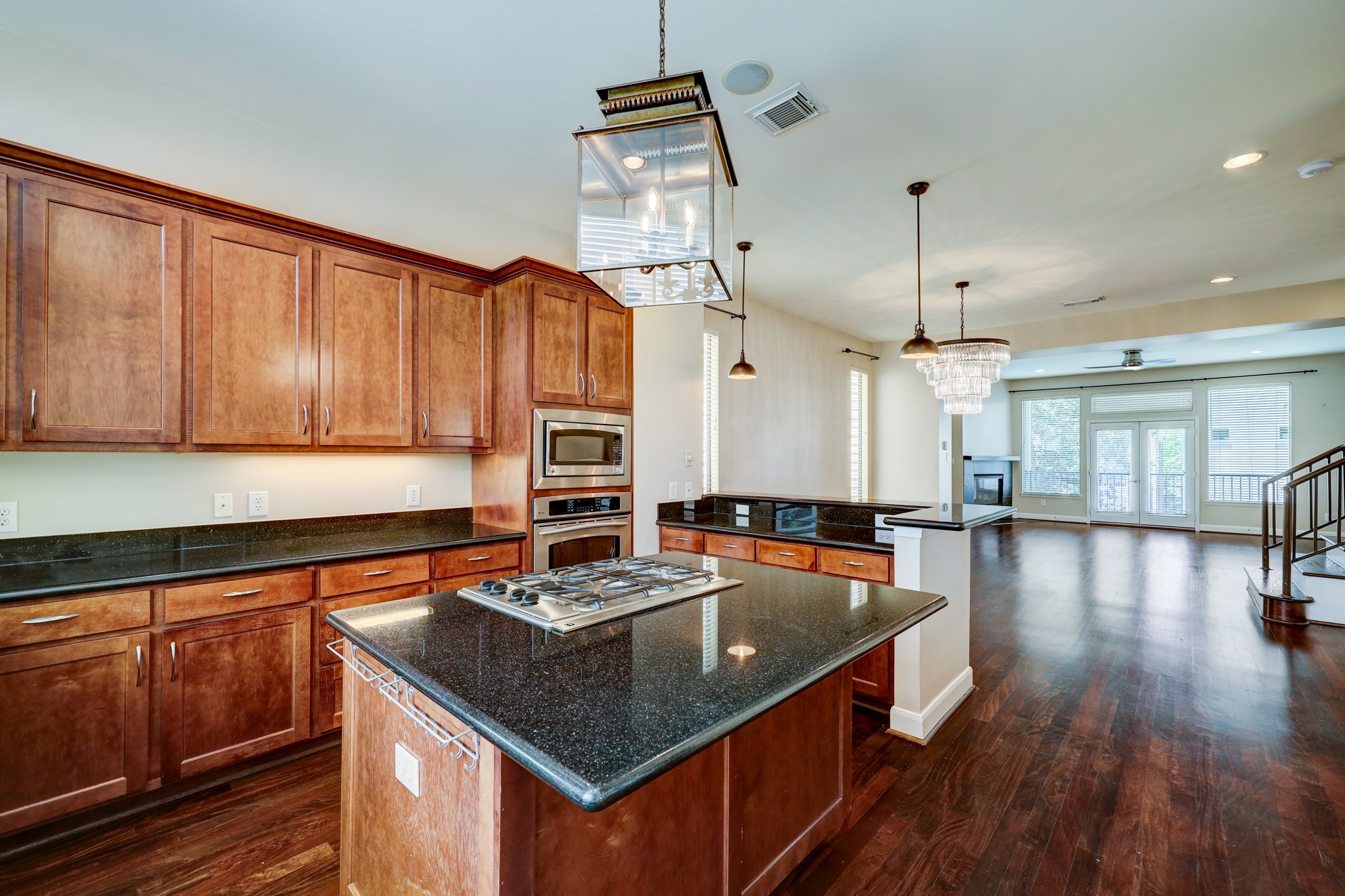 5202 Rose Street, Unit B Houston, TX 77007 - Photo 17 of 40 This inviting home features an open-concept kitchen and living area with rich hardwood floors, elegant pendant lighting, and ample natural light. The kitchen boasts modern appliances, granite countertops, and a spacious island, ideal for cooking and entertaining. The living area includes large windows and a cozy fireplace, creating a warm, welcoming ambiance.