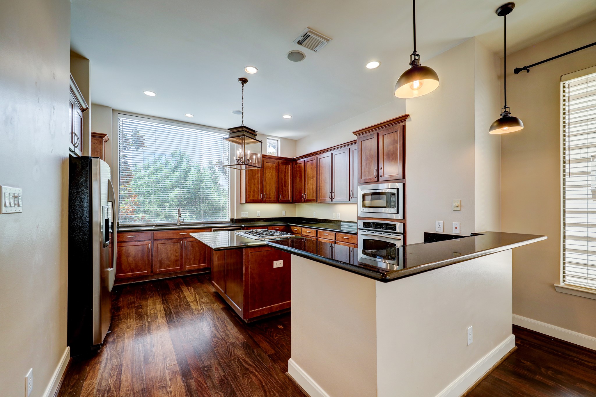 5202 Rose Street, Unit B Houston, TX 77007 - Photo 19 of 40 Modern kitchen with sleek dark countertops, stainless steel appliances, and rich wooden cabinetry. Features a large window for natural light and stylish pendant lighting.