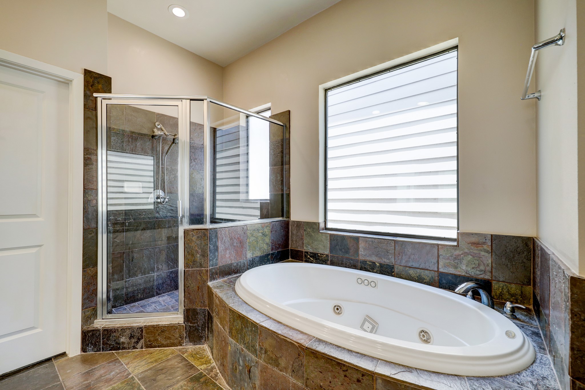 5202 Rose Street, Unit B Houston, TX 77007 - Photo 20 of 40 This bathroom features a luxurious spa-style jetted tub and a modern glass-enclosed shower, complemented by elegant tile work and ample natural light from the large window.