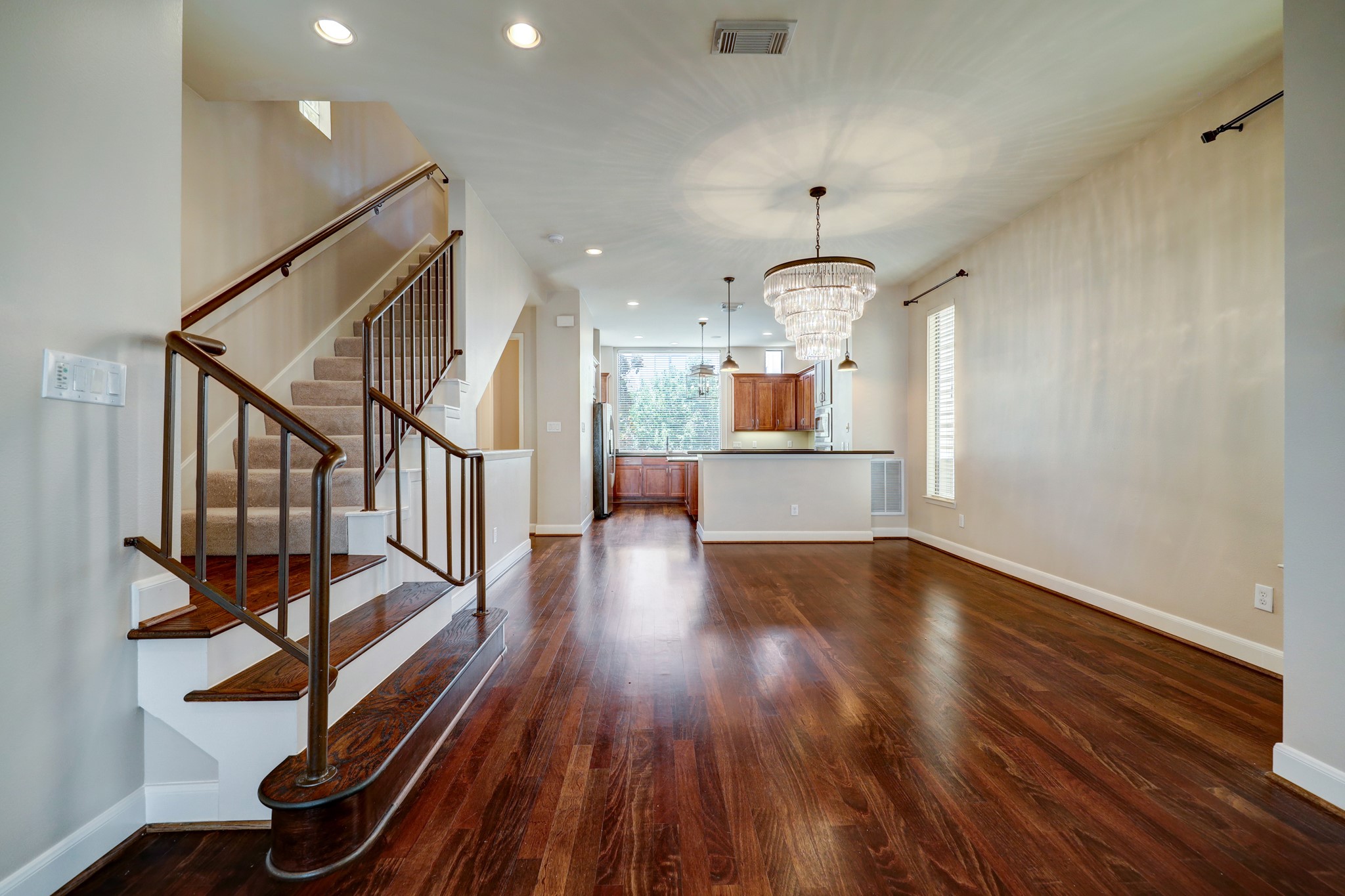 5202 Rose Street, Unit B Houston, TX 77007 - Photo 21 of 40 This inviting home features an open layout with rich hardwood floors, a stylish staircase, and a modern kitchen with a breakfast bar. Ample natural light enhances the spacious living and dining area, perfect for entertaining.