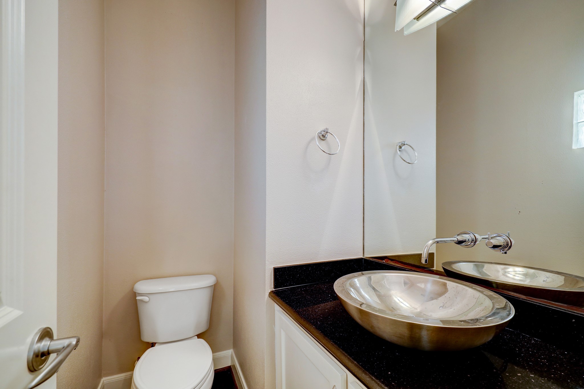 5202 Rose Street, Unit B Houston, TX 77007 - Photo 27 of 40 This photo shows a modern half-bathroom featuring a sleek vessel sink with a wall-mounted faucet, a toilet, and a large mirror. The space is clean and minimalistic, with neutral tones and a touch of elegance.