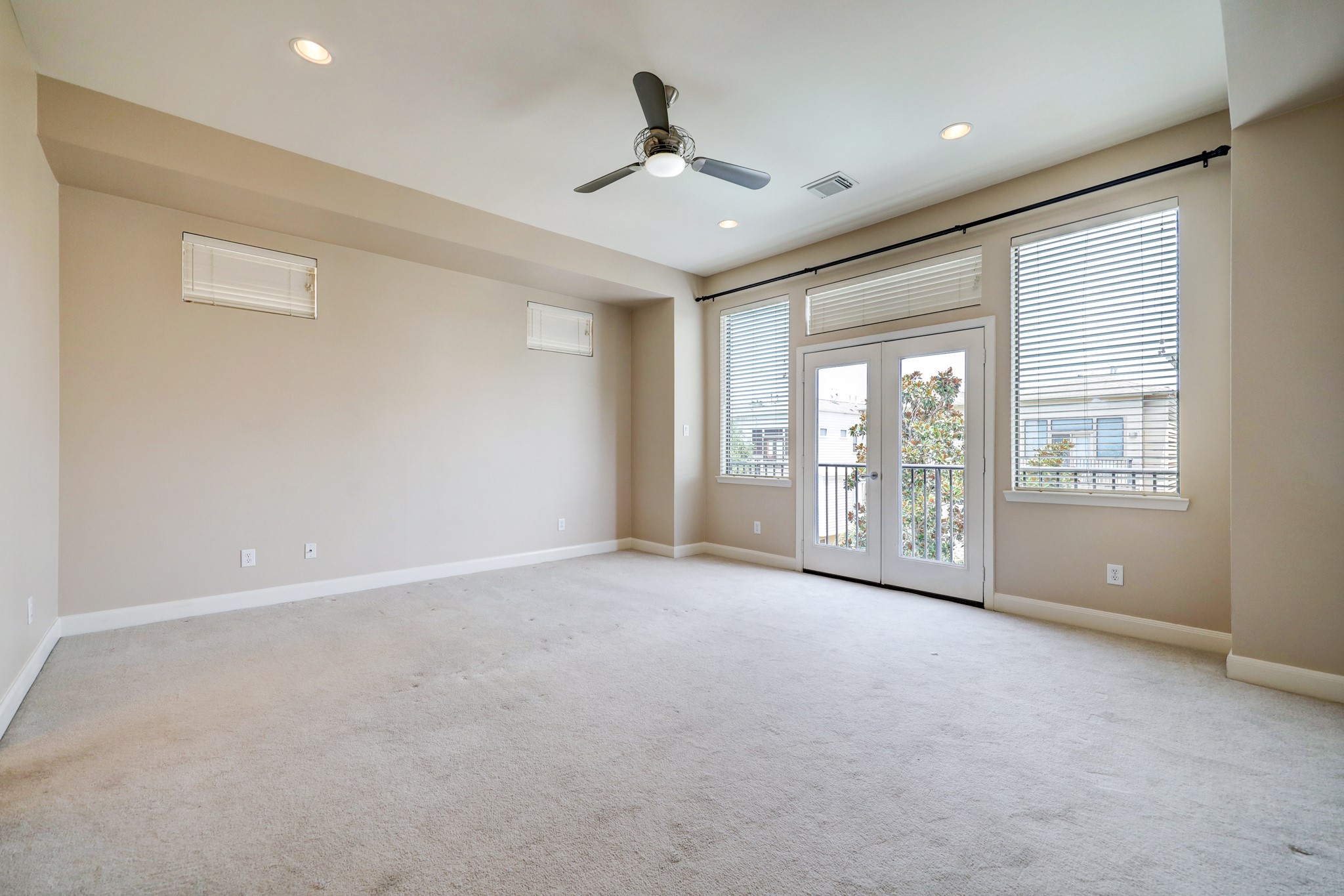 5202 Rose Street, Unit B Houston, TX 77007 - Photo 28 of 40 Spacious, well-lit room with neutral colors, featuring large windows and a ceiling fan. French doors open to a small balcony, offering plenty of natural light.