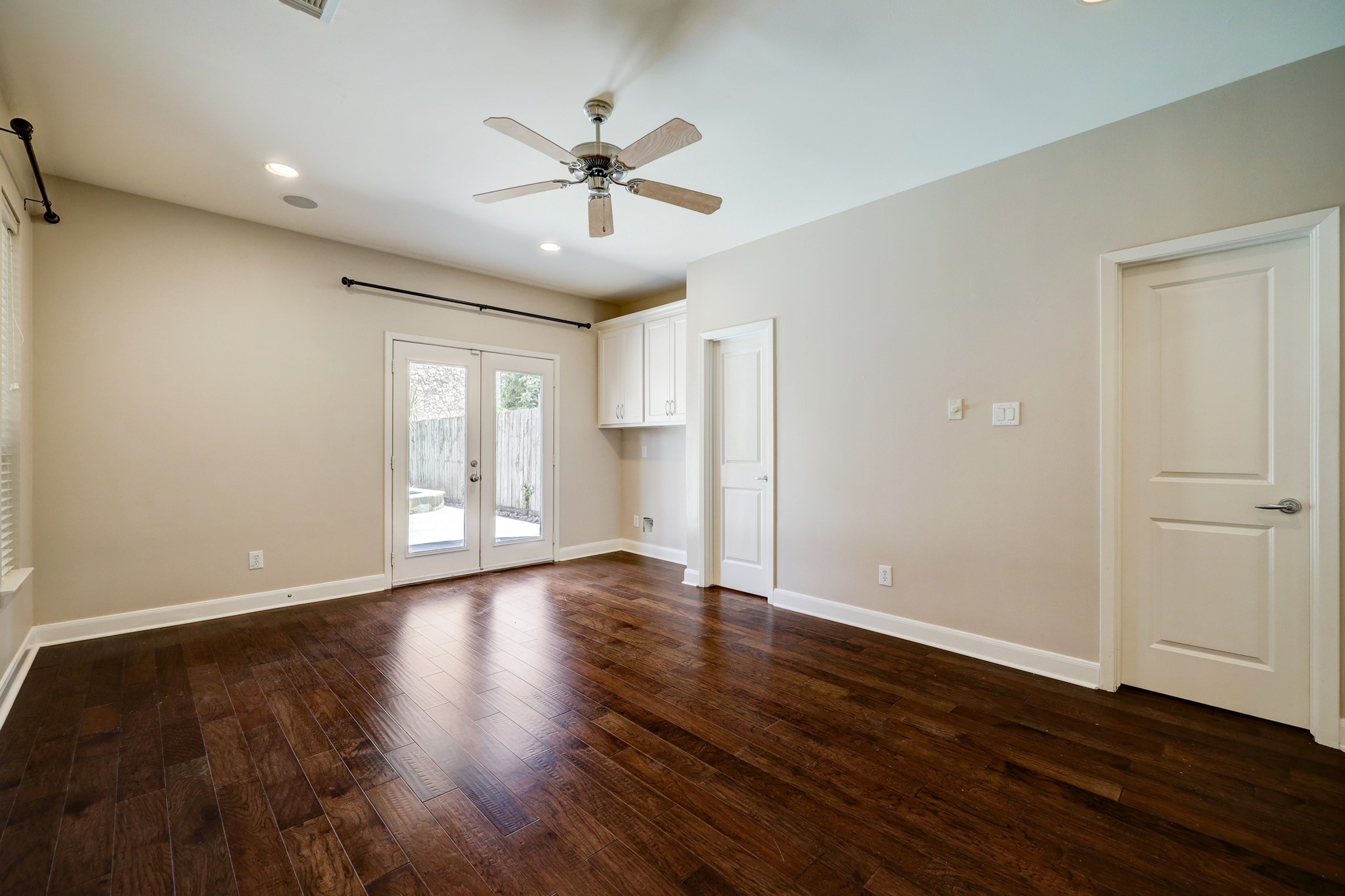 5202 Rose Street, Unit B Houston, TX 77007 - Photo 33 of 40 This room features rich hardwood floors, neutral walls, and recessed lighting. It includes a ceiling fan and double doors that open to a patio, offering plenty of natural light.