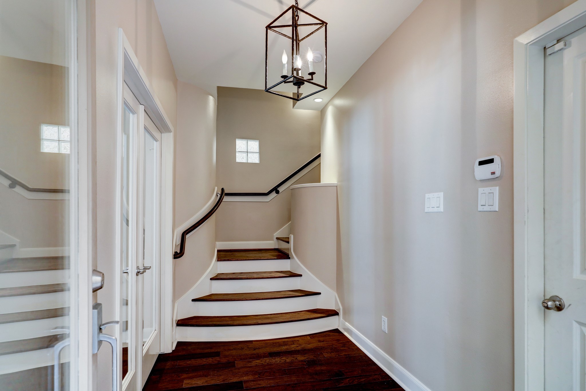 5202 Rose Street, Unit B Houston, TX 77007 - Photo 35 of 40 This photo showcases a bright, modern staircase with elegant dark wood steps and white risers. The area features a contemporary light fixture and neutral walls, creating a welcoming entryway.