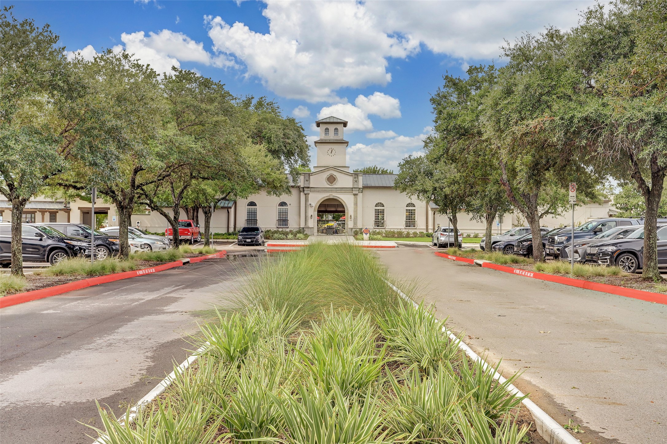 5202 Rose Street, Unit B Houston, TX 77007 - Photo 40 of 40 This photo shows a charming building with a clock tower, surrounded by trees and ample parking. The entrance is welcoming, and the landscaping is well-maintained, creating an attractive setting.