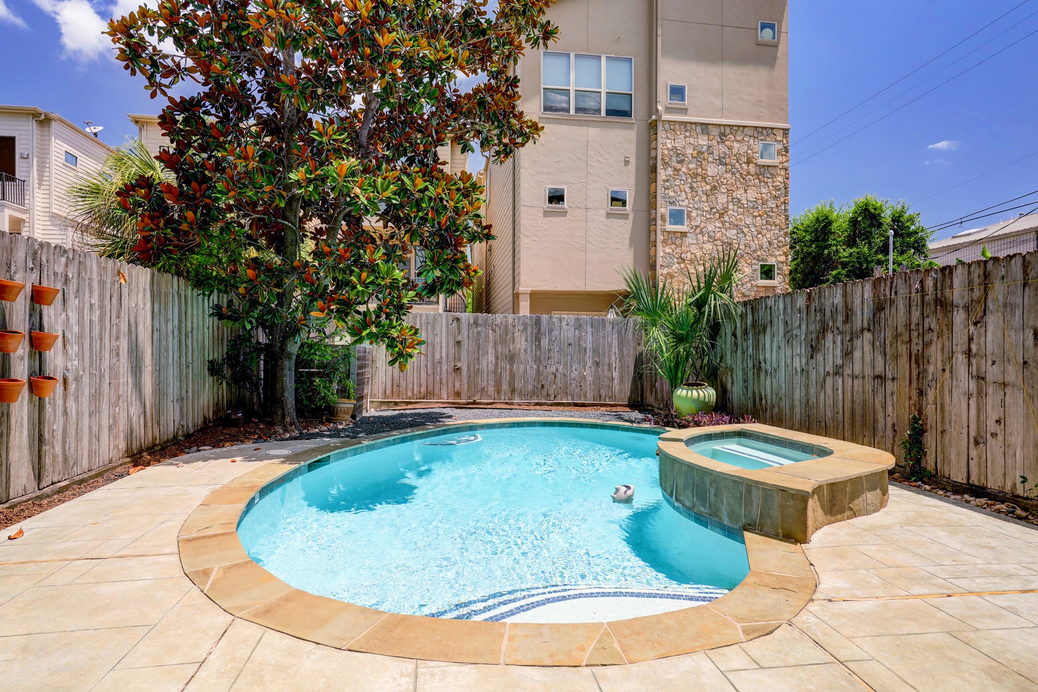 5202 Rose Street, Unit B Houston, TX 77007 - Photo 8 of 40 This backyard features a cozy swimming pool with an attached spa, surrounded by a wooden fence for privacy. A large tree provides shade, and there are planters on the fence for added greenery. Ideal for relaxation and outdoor enjoyment.