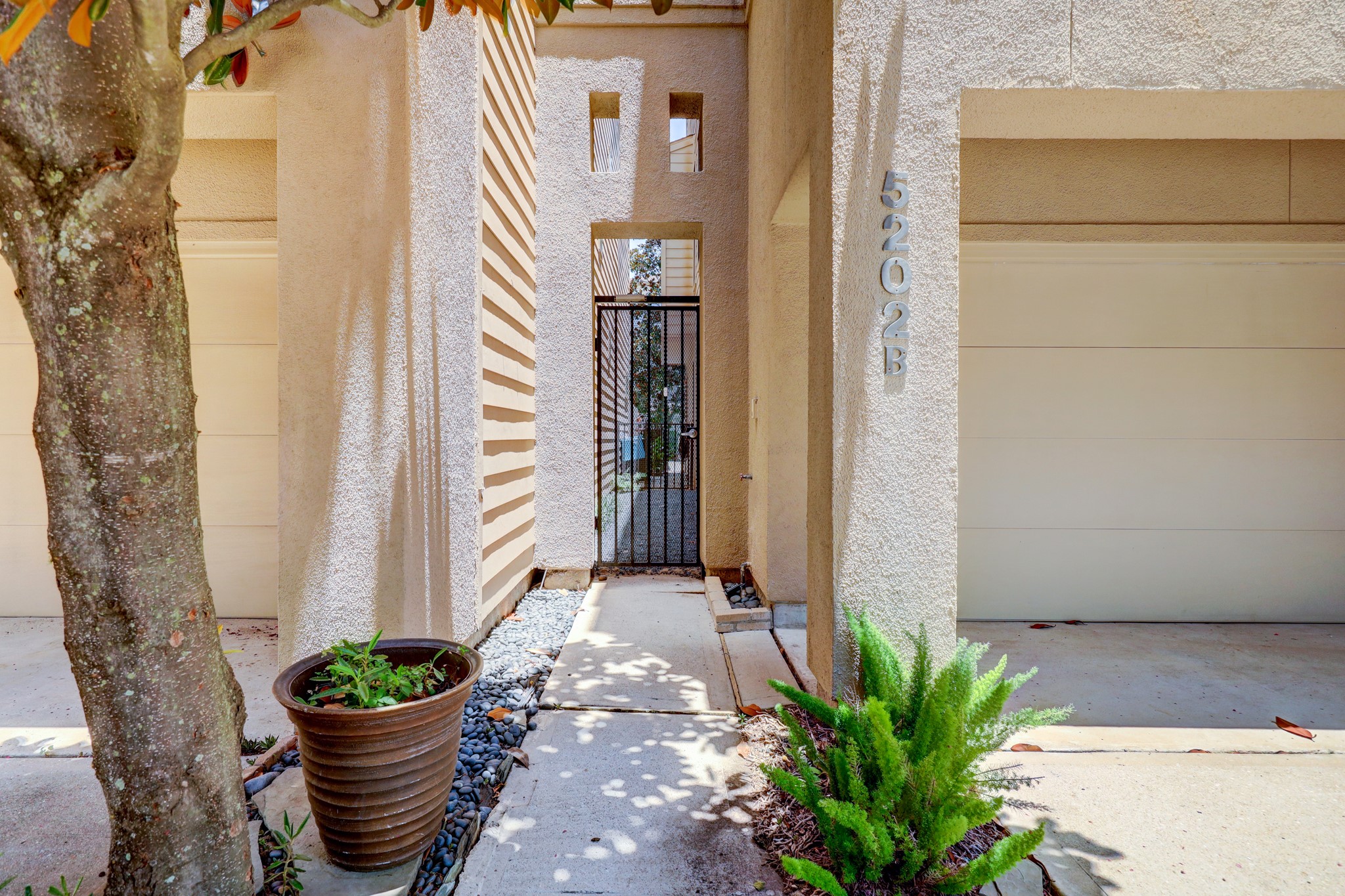 5202 Rose Street, Unit B Houston, TX 77007 - Photo 9 of 40 Modern entrance with a gated entryway flanked by two garages. The area is accented with potted plants and clean architectural lines, offering a welcoming and stylish curb appeal.