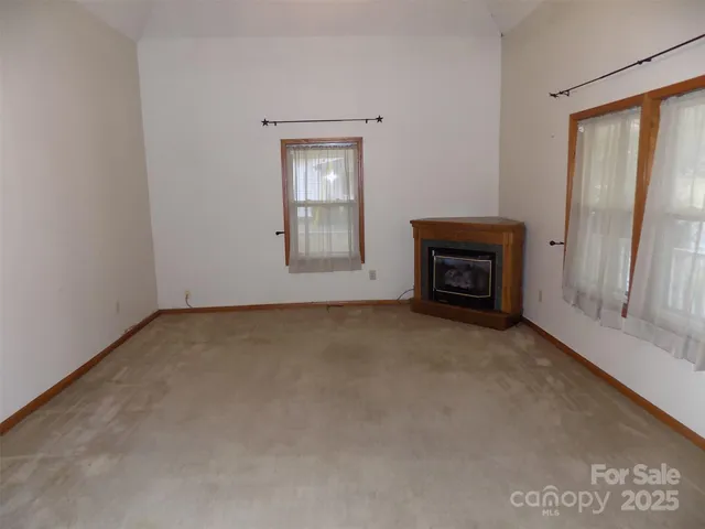 an empty room with a fireplace and windows