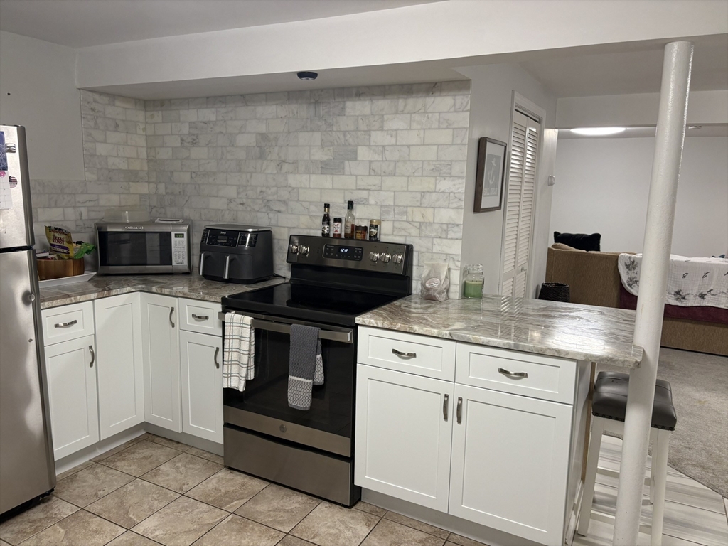 55 Fox Hill Road, Unit 1 Nahant, MA 01908 - Photo 8 of 9 a kitchen with white cabinets and appliances