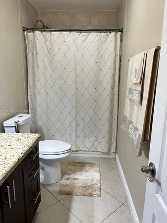 a bathroom with a granite countertop toilet and a sink