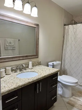 a bathroom with a granite countertop toilet sink and mirror