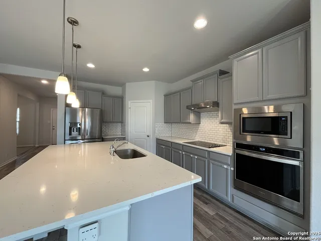 a kitchen with stainless steel appliances a kitchen island hardwood floor sink and stove