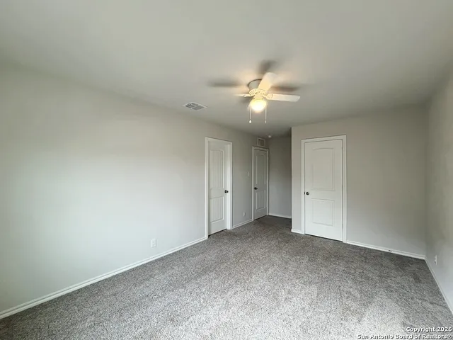 an empty room with a chandelier fan and windows