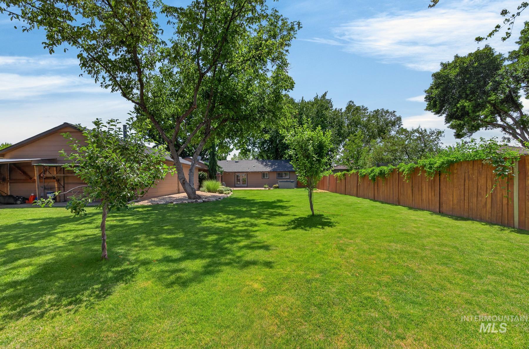 9622 Delaware Street Boise, ID 83709 - Photo 43 of 48 Expansive green lawn framed by a tall wooden privacy fence with climbing foliage