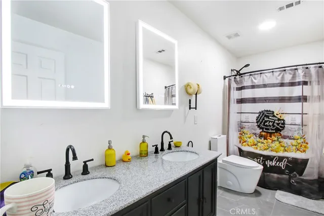 a bathroom with a granite countertop toilet sink and mirror