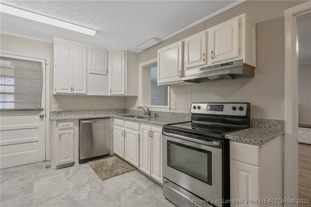 4914 Pinewood Drive Hope Mills, NC 28348 - Photo 6 of 36 a kitchen with granite countertop white cabinets and appliances