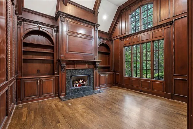 an empty room with wooden floor fireplace and windows