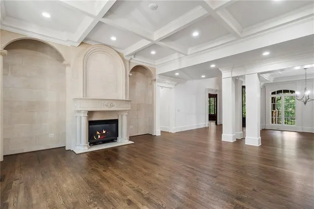 a view of an empty room with wooden floor fireplace and a window