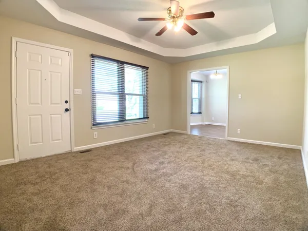 an empty room with windows and fan chandelier fan