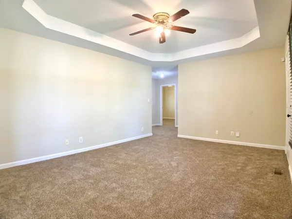 an empty room with windows and fan