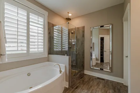 a bathroom with a tub a sink and a large window