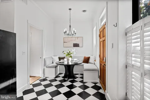 a living room with a black white checkered floor with a dining table and chairs