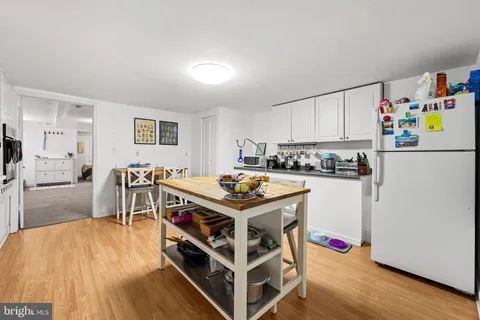 a kitchen with kitchen island a stove a refrigerator and a dining table with wooden floor