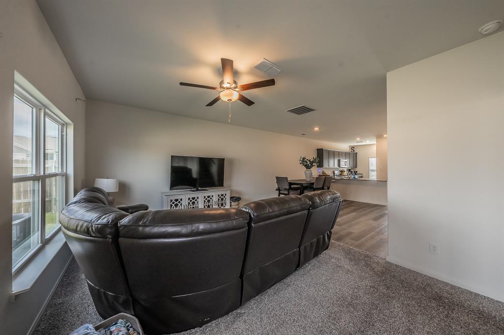 8125 White Sulphur Road Ponder, TX 76259 - Photo 11 of 38 Open-concept living space with a vaulted ceiling, ceiling fan with integrated lighting, large window with ample natural light, and plush grey carpeting
