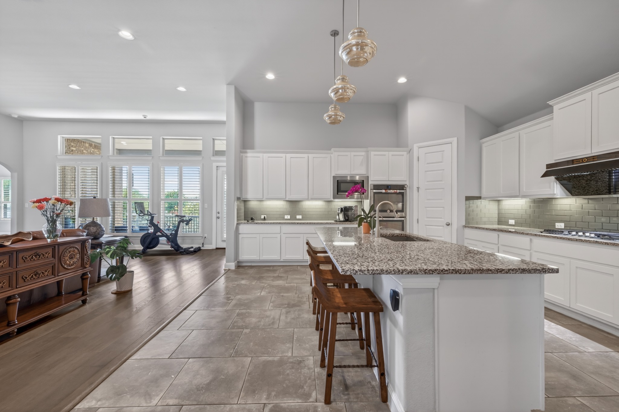 4105 Haight Street Round Rock, TX 78681 - Photo 14 of 40 Spacious kitchen featuring an expansive island with granite countertops, white cabinetry, integrated stainless steel appliances, and a subway tile backsplash