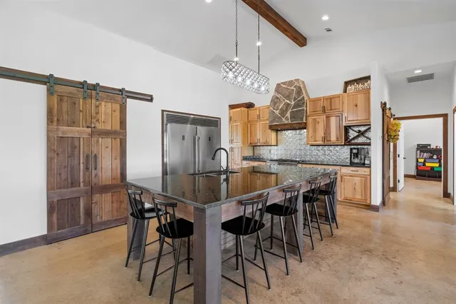 a kitchen with stainless steel appliances kitchen island a table and chairs in it