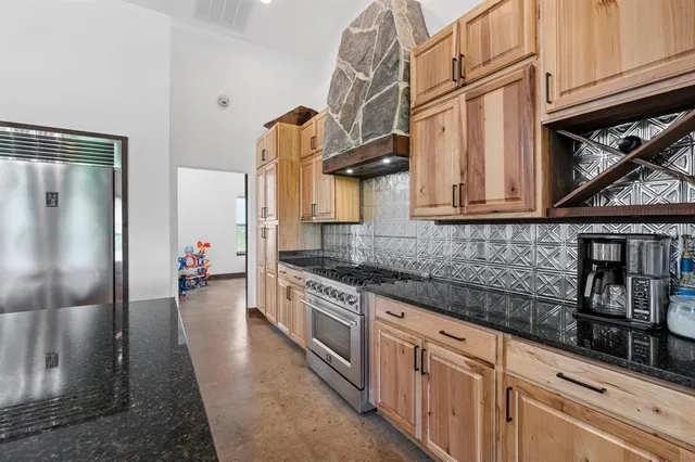 a kitchen with stainless steel appliances granite countertop a refrigerator a stove and a sink