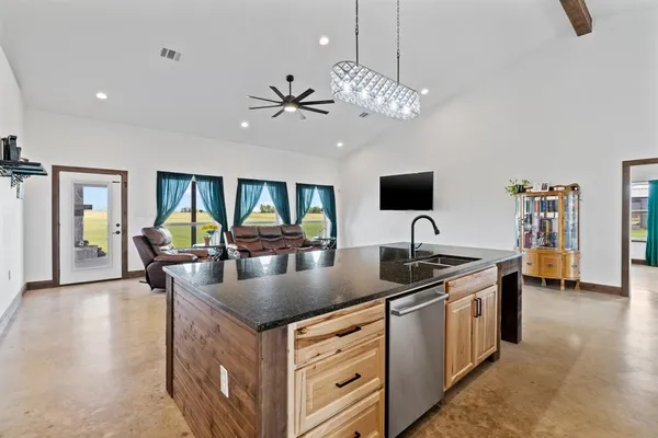 a kitchen with granite countertop a sink counter top space and living room