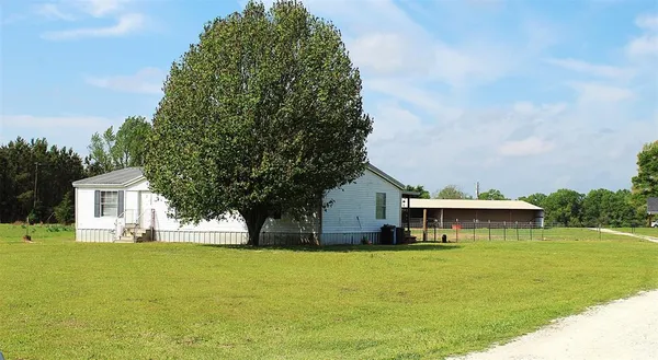 a front view of a house with a garden and trees