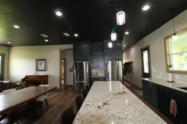 a large room with stainless steel appliances kitchen island granite countertop a large kitchen island sink and a refrigerator