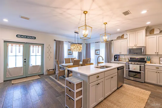 a open kitchen with stainless steel appliances granite countertop a sink dishwasher a stove a dining table and chairs with wooden floor