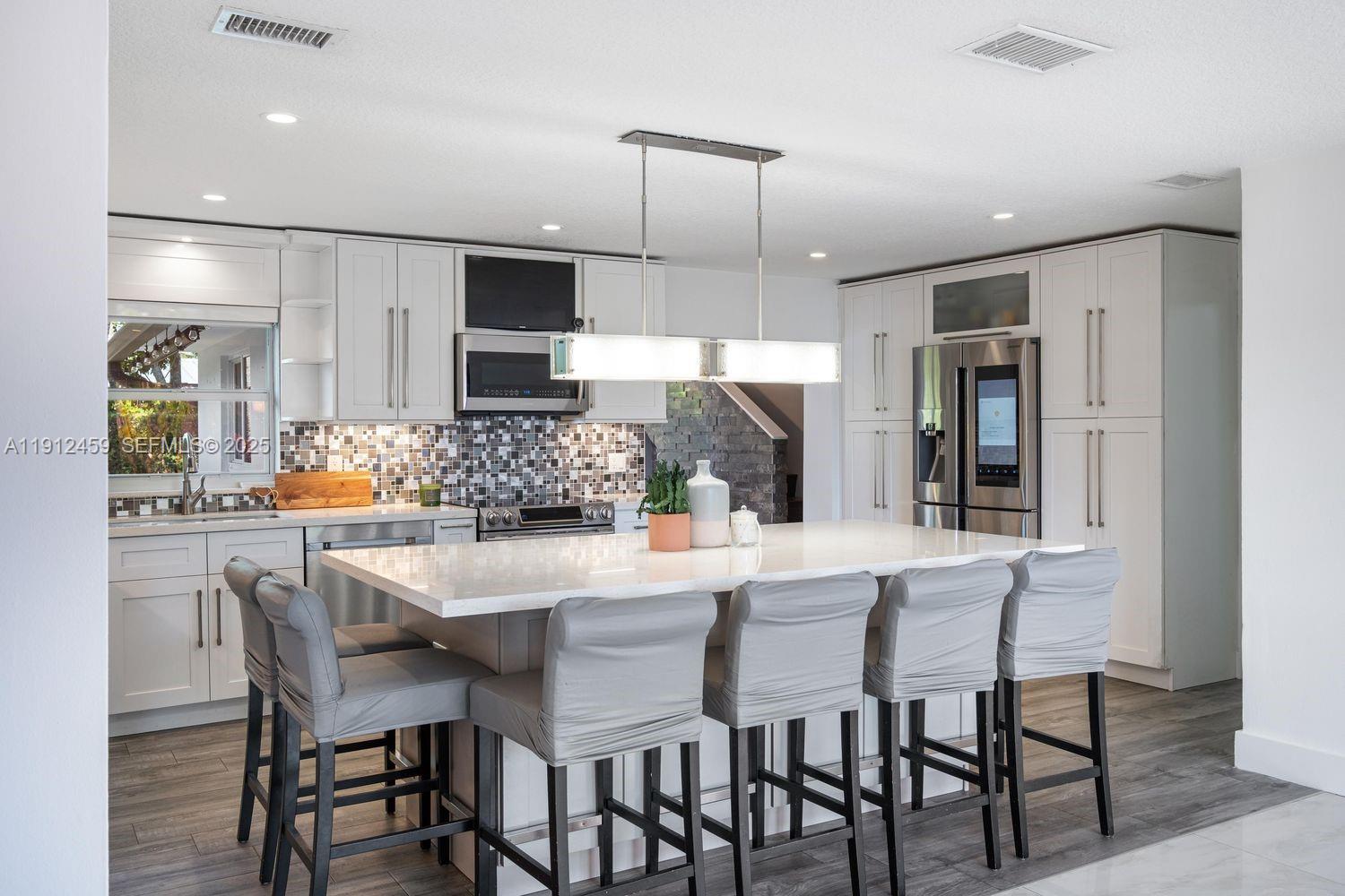 10025 Southwest 83rd Street Miami, FL 33173 - Photo 5 of 37 a kitchen with stainless steel appliances kitchen island granite countertop a dining table chairs and sink