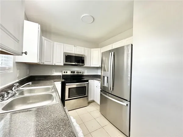 a kitchen with stainless steel appliances granite countertop a refrigerator a stove a sink and a microwave