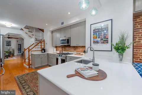 a kitchen with stainless steel appliances kitchen island granite countertop a refrigerator a stove and a sink with wooden floor