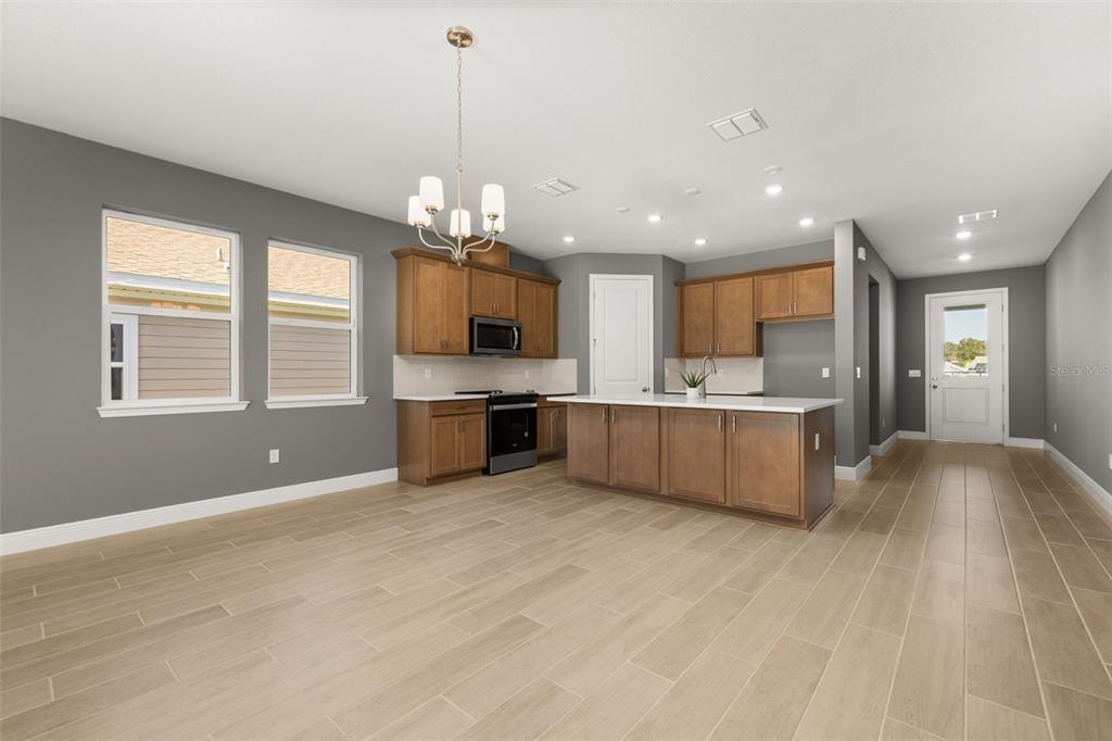 985 Fiesta Key Circle Lady Lake, FL 32159 - Photo 6 of 34 a large kitchen with kitchen island a sink dishwasher a stove and a large window with wooden floor