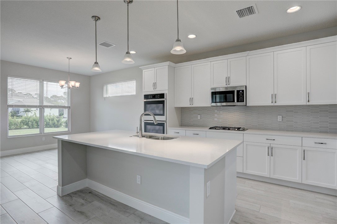 6423 High Pointe Circle Vero Beach, FL 32967 - Photo 15 of 36 a kitchen with kitchen island granite countertop a sink appliances cabinets and a counter top space