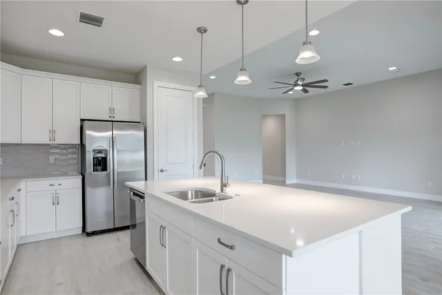 a kitchen with stainless steel appliances a refrigerator sink and white cabinets