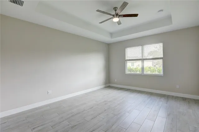 an empty room with wooden floor ceiling fan and windows